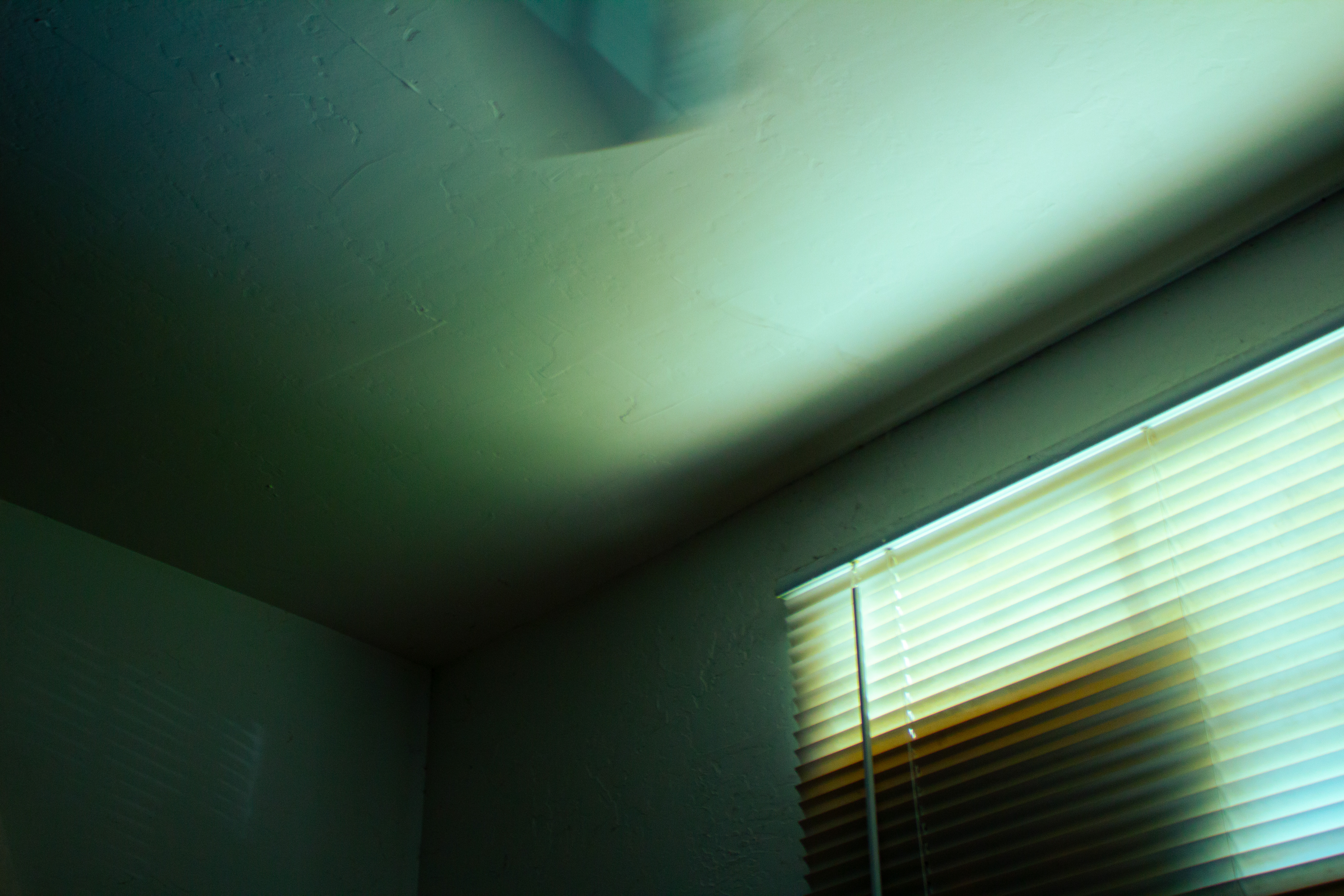 A corner of a room bathed in ominous, ambient blue light.