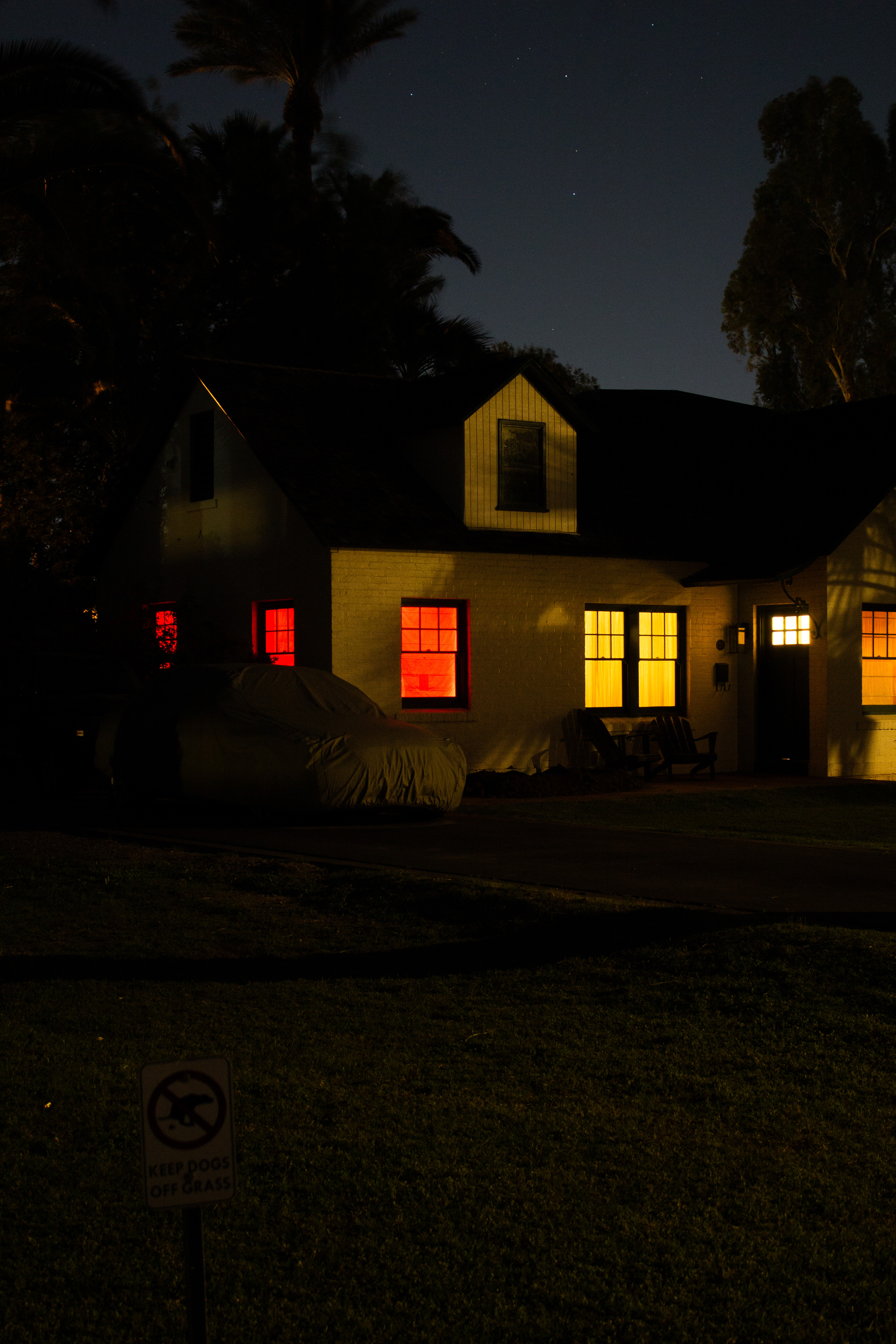 A lone house with glowing orange windows bathed in ominous ambient light.